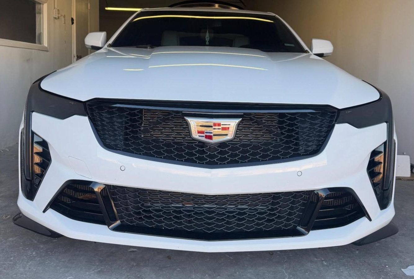 White Cadillac with blacked-out headlights