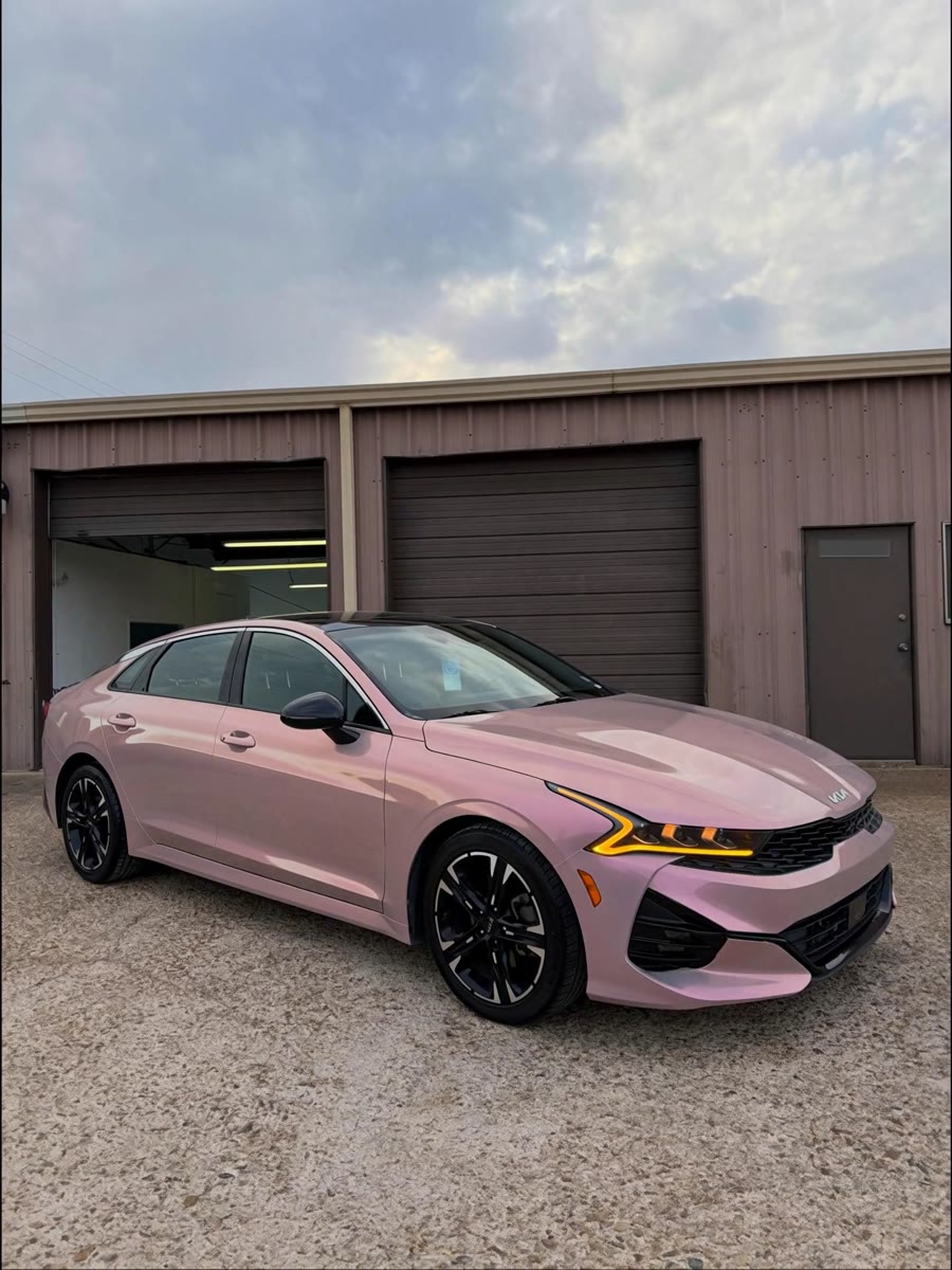 The Kia K5 after its wrap, in gloss blush pink, outside the shop